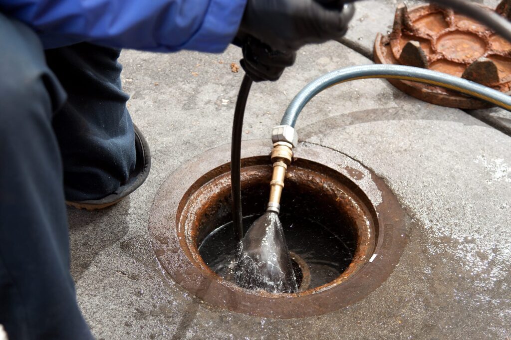 Plumber hydro jetting a sewer line through a manhole in Palm Coast