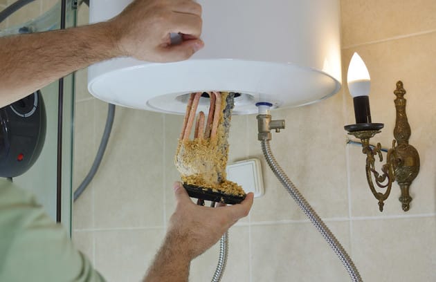 Technician removing mineral buildup from a water heater in Palm Coast